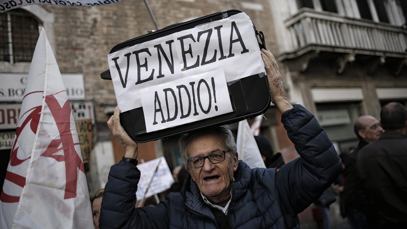 A man holds up a sign reading Venice Farewell during a protest